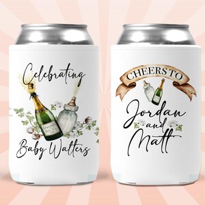 Puede incluir: Dos neveras de bebidas blancas con un dise&ntilde;o que presenta botellas de champ&aacute;n, biberones y detalles florales. El texto en las neveras dice "Celebrating Baby Watters" y "Cheers to Jordan and Matt".