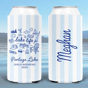 May include: Two slim can coolers featuring a light blue and white vertical striped pattern. One cooler displays blue line art icons of lake activities, the text "lake life", "Portage Lake", "GIRLS WEEKEND 2025". The other cooler features the name "Meghan".