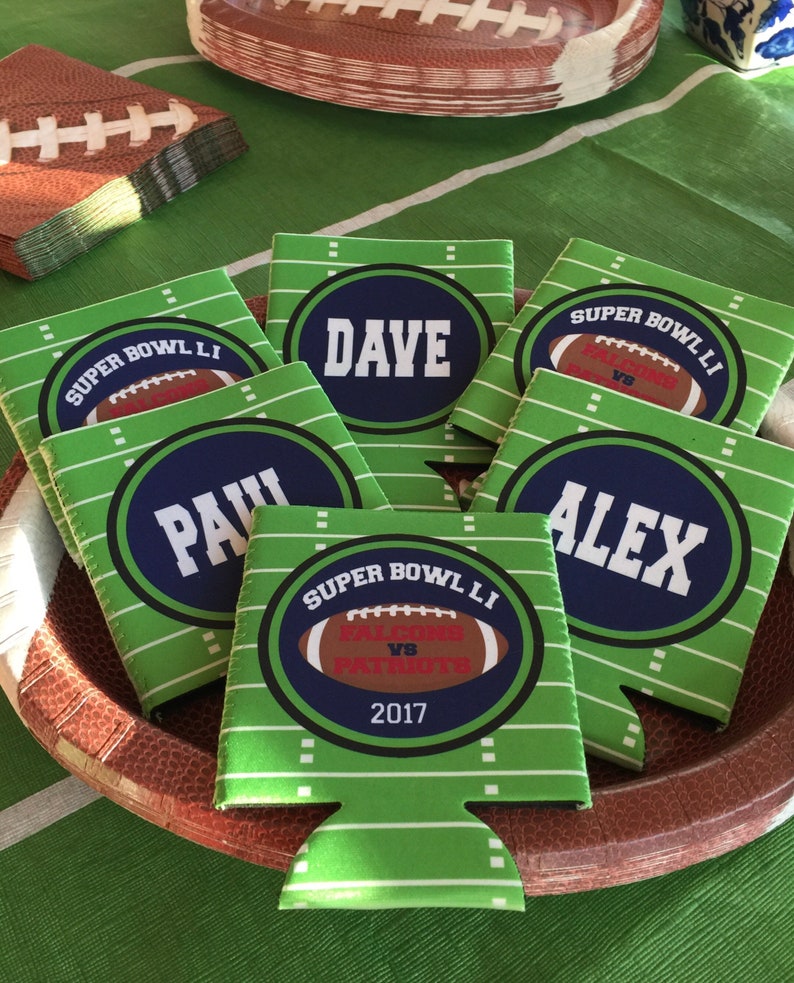 Pode incluir: Seis coolers de lata verdes e azuis com texto branco. Os coolers apresentam um design de campo de futebol e o texto "SUPER BOWL LI" e "2017". Os nomes "Dave", "Paul" e "Alex" tamb&eacute;m est&atilde;o nos coolers.