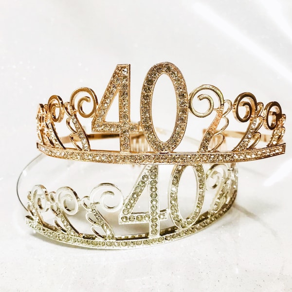 May include: Two decorative tiaras, one gold and one silver, each featuring the number "40" encrusted with rhinestones. The gold tiara is on top, with a delicate, scrolled design. The silver tiara is below, with a similar design.