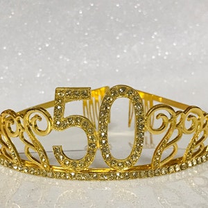 May include: Gold-colored tiara with rhinestones, featuring the number "50" in the center.