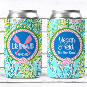 May include: Two aluminum can coolers with a colorful floral pattern in blue, green, and pink. One cooler features the text "Lake Norman, NC" and "09.06.2020" inside a blue circle with pink crossed oars. The other cooler says "Megan & Reid Tie the Knot".