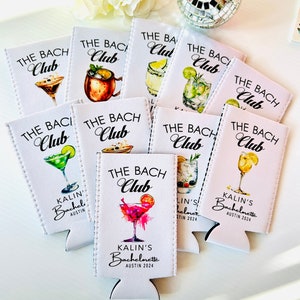 Pu&ograve; includere: Un set di nove refrigeratori per lattine bianchi con il testo "The Bach Club" e varie illustrazioni di cocktail. I refrigeratori hanno il testo "Kalin's Bachelorette Austin 2024" stampato su di essi.