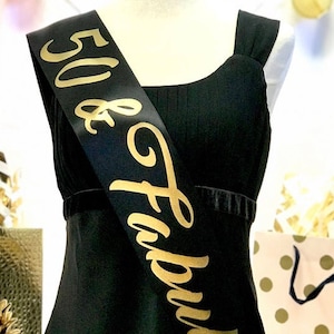 May include: Black satin sash with gold lettering that reads "50 & Fabulous".