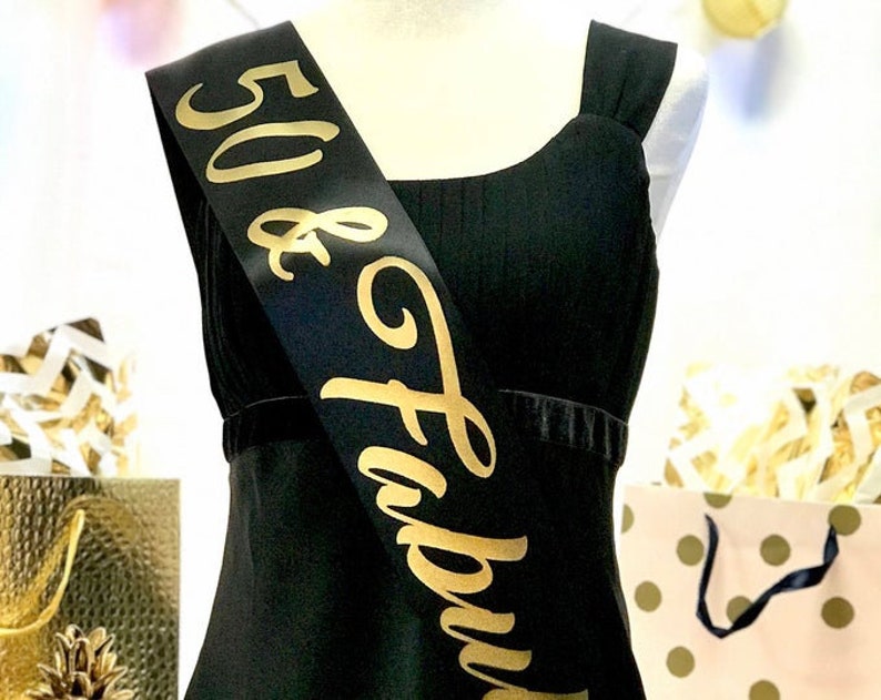 May include: Black satin sash with gold lettering that reads "50 & Fabulous".