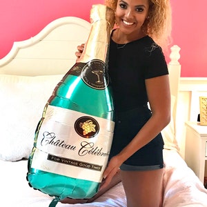 May include: A large green and gold foil balloon shaped like a champagne bottle. The balloon has the text "Chateau Celebrate" and "For Vintage Good Times" printed on it.