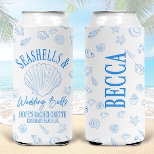May include: Two white foam can coolers featuring a blue seashell pattern. The left cooler displays the text SEASHELLS & Wedding Bells, HOPE'S BACHELORETTE, ROSEMARY BEACH, FL. The right cooler features the name BECCA printed vertically in blue.