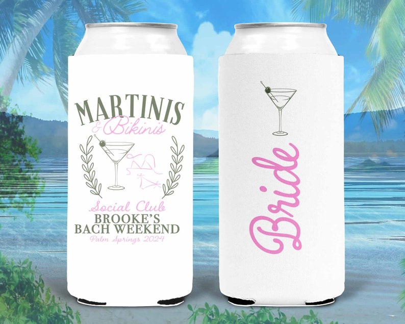 May include: Two white can coolers with a pink and gray design. One cooler says "Martini's & Bikinis" with a martini glass and a wreath. The other cooler says "Bride" in pink cursive.