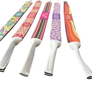 May include: Five colorful eyeglass straps with various patterns and names. Designs include floral, geometric, and rainbow patterns. The names "Maria", "Makeda", "Fiesta", "Robyn", and "Kate" are printed on the straps.