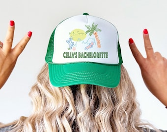 May include: Green and white trucker hat with a palm tree and the text "Palm Springs" and "Celia's Bachelorette" on the front.