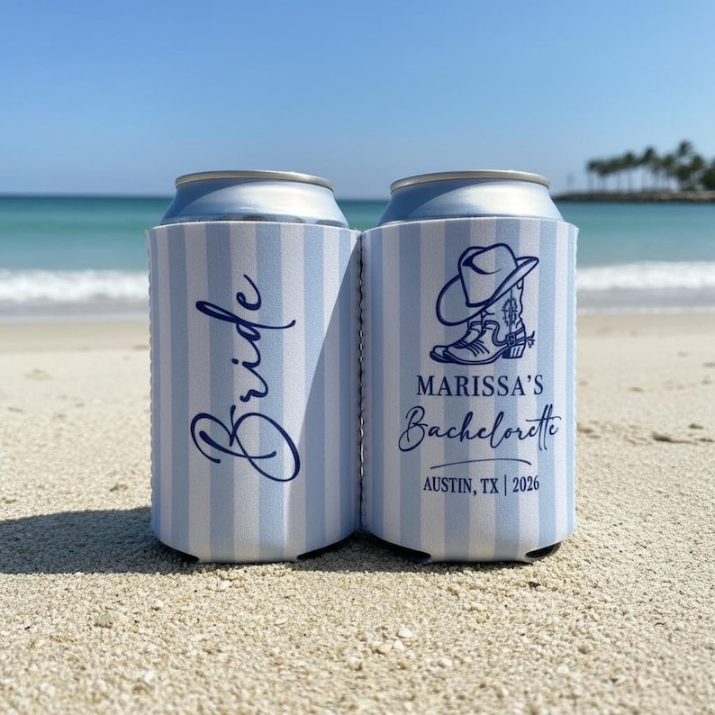 May include: Two blue and white striped can coolers on a sandy beach. One cooler says "Bride" in cursive, the other says "Marissa's Bachelorette" with a cowboy boot and hat graphic, and "Austin, TX | 2026".