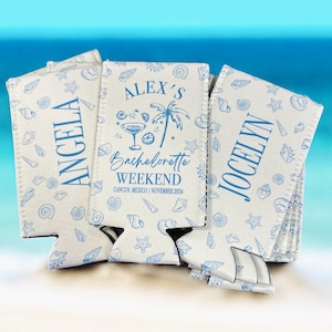 May include: Three white foam can coolers featuring a blue seashell pattern. The center cooler displays the text "ALEX'S BACHELORETTE WEEKEND CANCUN, MEXICO | NOVEMBER 2024" with a martini glass and palm tree icon. The side coolers are personalized with "ANGELA" and "JOCELYN".