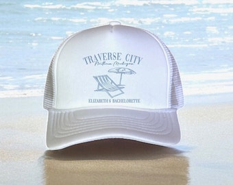 May include: White trucker hat with a blue graphic of a beach chair and umbrella with the text "Traverse City, Northern Michigan" and "Elizabeth's Bachelorette" printed on the front.