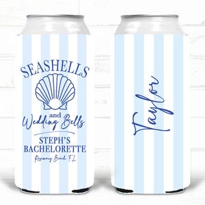 May include: A pair of blue and white striped can coolers. One cooler features the text "Seashells and Wedding Bells" with a seashell graphic. The other cooler has the name "Taylor" in script.