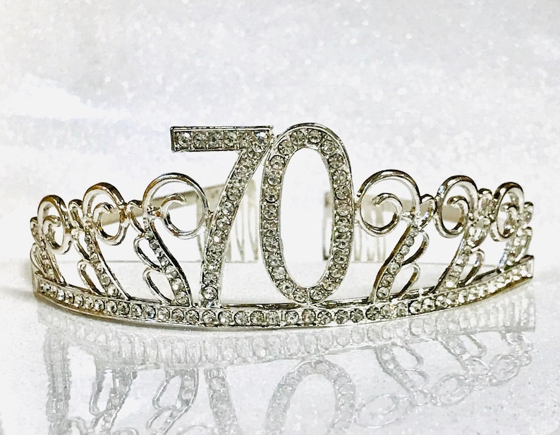 May include: Silver-toned tiara with the number 70 in sparkling rhinestones. The tiara features an ornate, scrollwork design and a comb for secure placement in the hair. A celebratory accessory for a milestone birthday.