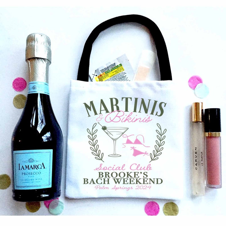 May include: White tote bag with a black handle and the text "Martinis & Bikinis Social Club Brooke's Bach Weekend Palm Springs 2024" printed on it. The bag is filled with a bottle of prosecco, a small bottle of lotion, and a small bottle of lip gloss.