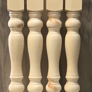 May include: Four unfinished wooden table legs with a turned design. The legs are approximately 16 inches tall and have a square top.