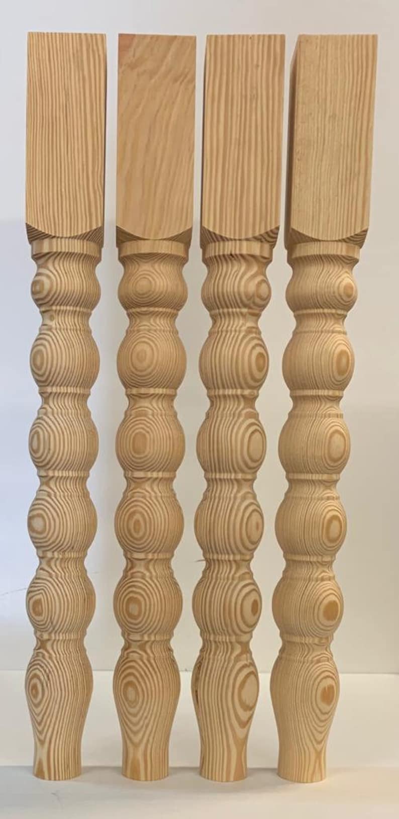 Puede incluir: Cuatro patas de mesa de madera torneada con un dise&ntilde;o decorativo, redondeado y bulboso. Las patas son de madera marr&oacute;n claro con un patr&oacute;n de veta natural.