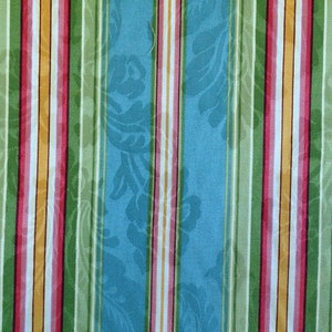 May include: A blue fabric with vertical stripes in green, pink, white, and yellow. The fabric has a subtle floral pattern.