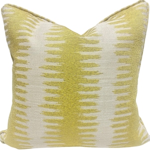 May include: A decorative throw pillow with a white and gold geometric pattern. The pillow is made of a soft, textured fabric.