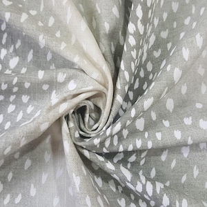 May include: A close-up of a gray fabric with a white deer print. The fabric is folded and has a soft, textured feel.