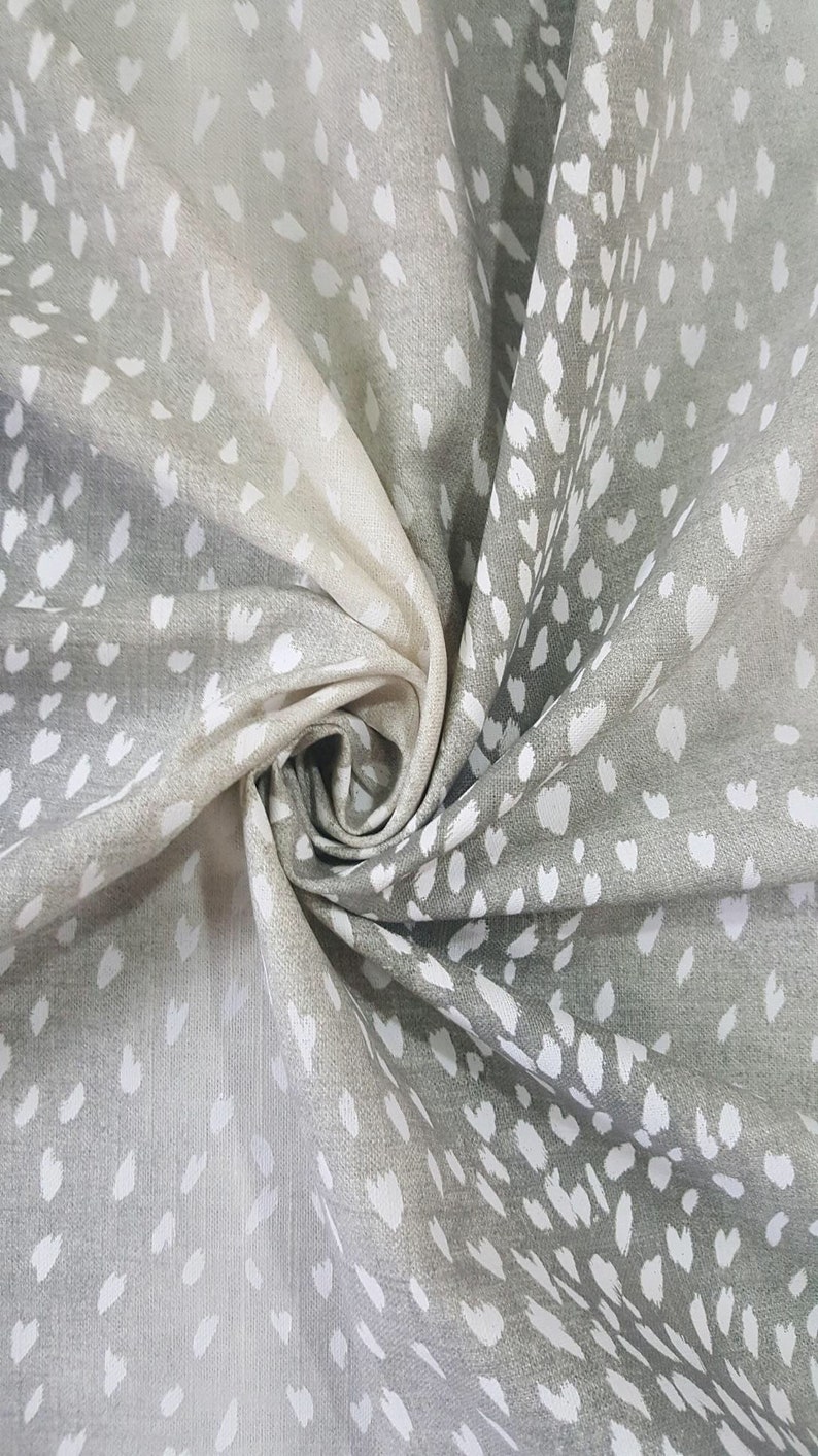May include: A close-up of a gray fabric with a white deer print. The fabric is folded and has a soft, textured feel.