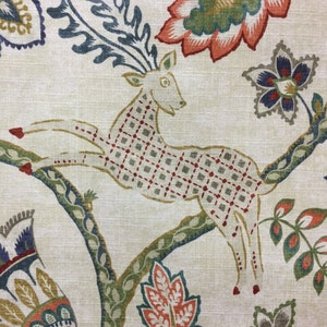 May include: A beige fabric featuring a repeating pattern of a leaping deer with a red and grey grid design on its body. The deer is surrounded by large, stylized floral motifs in shades of orange, blue, green, and yellow, set against a textured background.