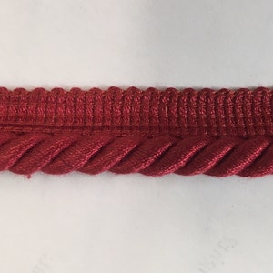 May include: Red braided trim with a woven top edge. This trim is perfect for adding a touch of elegance to any project.