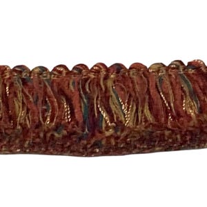 May include: Close-up of decorative fringe trim. The trim features a deep red base with accents of gold, green, and purple. The fringe is densely packed, creating a textured and luxurious appearance. Ideal for upholstery and craft projects.