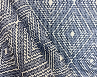 May include: A close-up of a fabric with a navy blue and white geometric pattern. The fabric has a textured, woven look and features a repeating diamond shape with a smaller diamond inside.