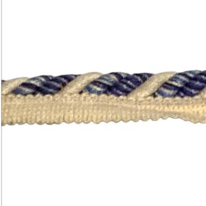 May include: Close-up of a decorative rope trim. The trim features a twisted rope design in shades of blue and white, with a beige scalloped edge. This trim is suitable for various craft and sewing projects.