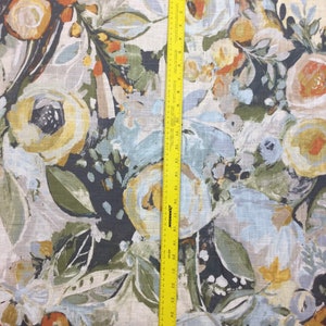 Pode incluir: Um close-up de um tecido com um padr&atilde;o floral. O tecido apresenta uma variedade de flores em tons de amarelo, laranja, azul e verde. O fundo &eacute; de cor bege claro.