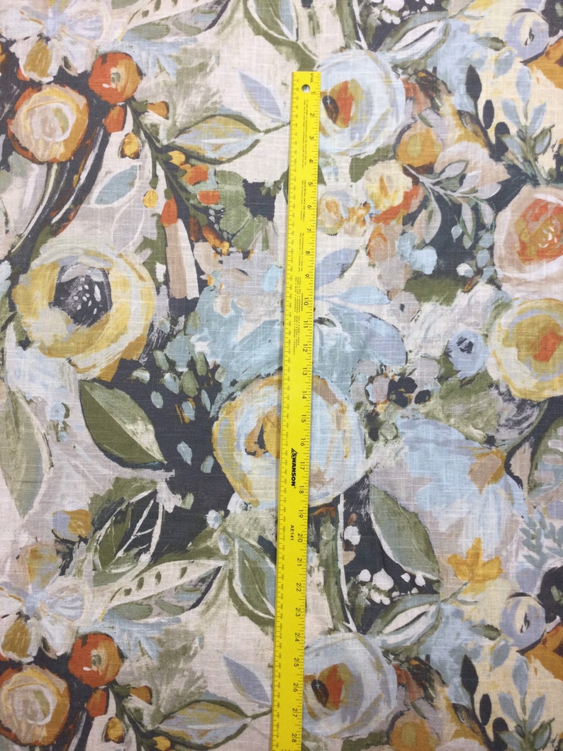 Pode incluir: Um close-up de um tecido com um padr&atilde;o floral. O tecido apresenta uma variedade de flores em tons de amarelo, laranja, azul e verde. O fundo &eacute; de cor bege claro.