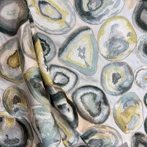 May include: Beige fabric with a repeating pattern of large, colorful agate slices. The agate slices are embroidered with shades of green, blue, yellow, and brown.