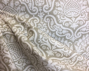 May include: Beige fabric with a white damask pattern. The fabric has a subtle texture and a slightly wrinkled appearance.