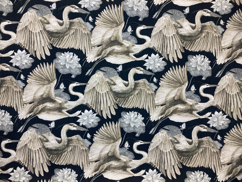 May include: A black fabric with a repeating pattern of white lotus flowers and gray herons with outstretched wings.