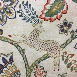 May include: A fabric featuring a repeating pattern of a leaping deer with a grid-like body design, surrounded by large stylized floral motifs in shades of orange, blue, green, and yellow on a light beige background with a visible woven texture.
