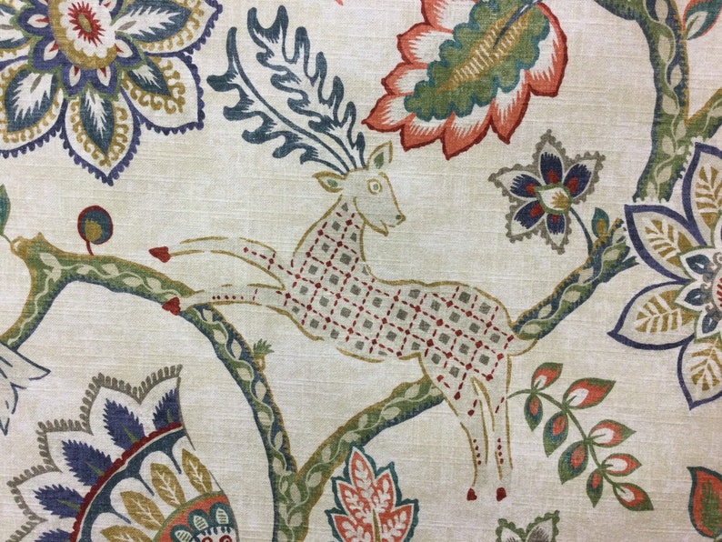 May include: A fabric featuring a repeating pattern of a leaping deer with a grid-like body design, surrounded by large stylized floral motifs in shades of orange, blue, green, and yellow on a light beige background with a visible woven texture.