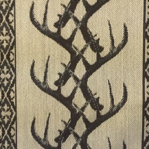May include: Beige fabric with a repeating pattern of black stylized deer antlers. The antlers are arranged in a criss-cross pattern.