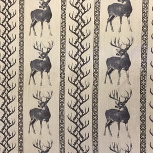 May include: A beige fabric with a repeating pattern of black deer and stylized antlers. The deer are facing right and have large antlers. The antlers are stylized and look like a series of connected branches.