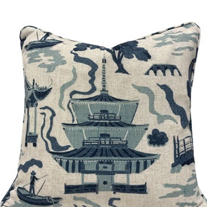 May include: Square decorative pillow with a blue and off-white Asian-inspired design. The pillow features a pagoda, boats, bridges, and trees. The color palette includes shades of blue and off-white, creating a serene and elegant aesthetic.