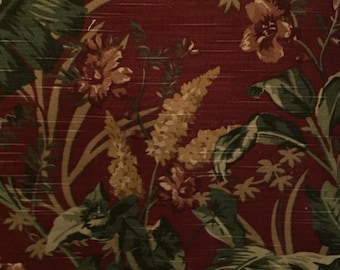 May include: A red fabric with a floral pattern featuring green leaves, brown flowers, and yellow flower buds.