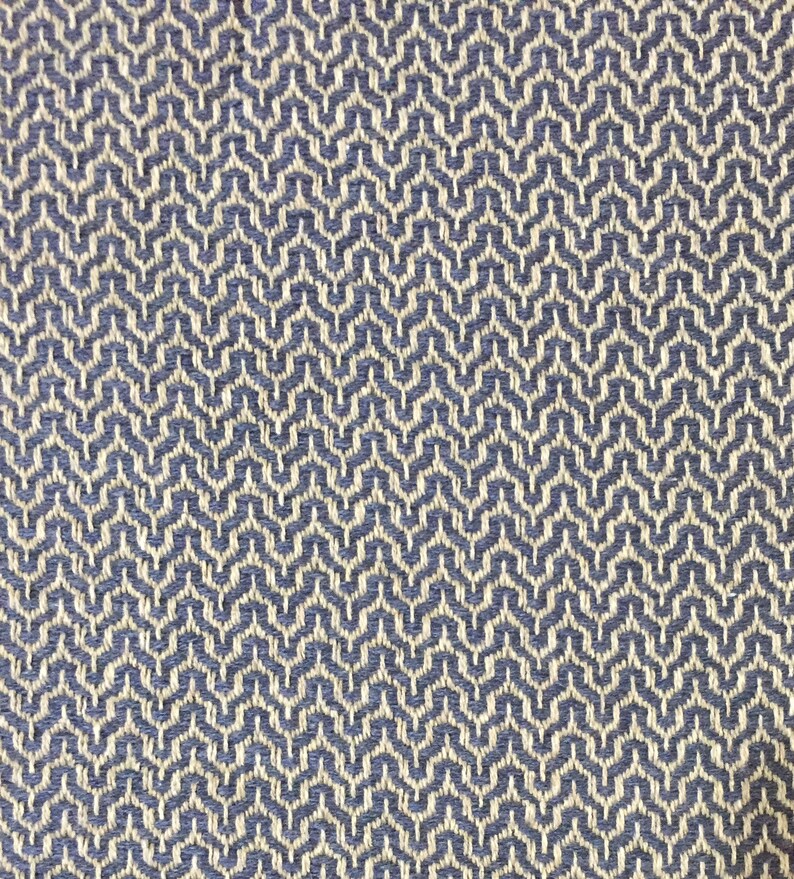 May include: A close-up of a woven fabric with a geometric pattern. The fabric is a light blue color with a white pattern.