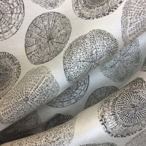 May include: White fabric with a repeating pattern of black and gray tree rings. The fabric has a subtle texture.