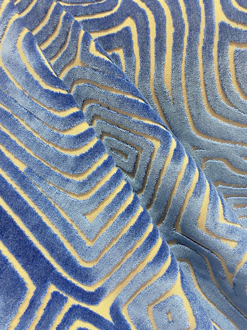 May include: Blue and beige patterned fabric with a textured, raised design. The fabric has a geometric pattern of overlapping lines and squares.