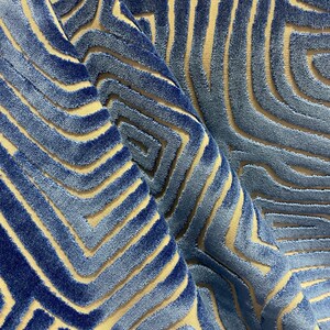 May include: Blue and beige patterned fabric with a textured, raised design. The fabric has a geometric pattern of overlapping lines and shapes.