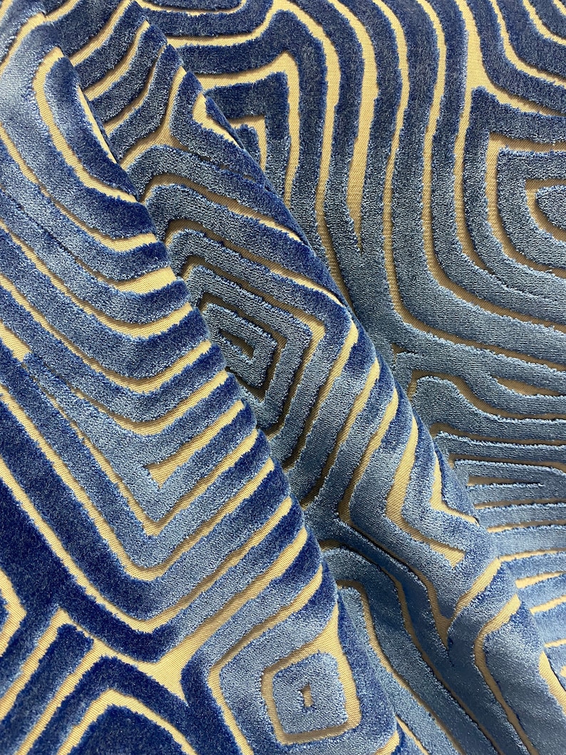 May include: Blue and beige patterned fabric with a textured, raised design. The fabric has a geometric pattern of overlapping lines and shapes.