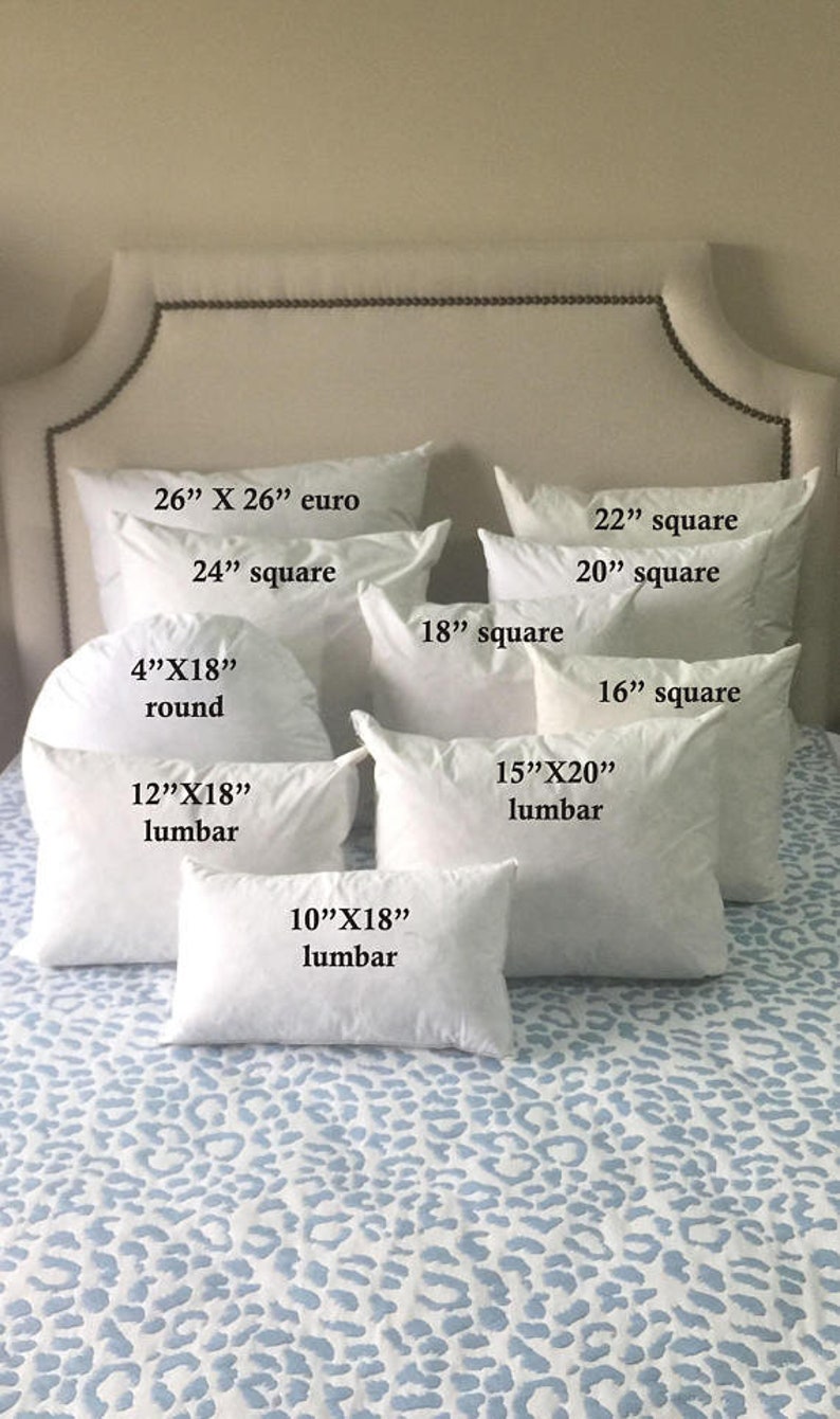 May include: A collection of white pillow inserts in various sizes and shapes, including square, round, and lumbar. The pillow inserts are arranged on a white and blue patterned bedspread. The sizes of the pillows are labeled in inches.