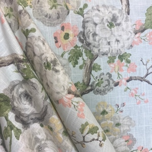 May include: A light blue fabric with a floral pattern. The flowers are in shades of pink, gray, and yellow. The fabric has a linen texture.