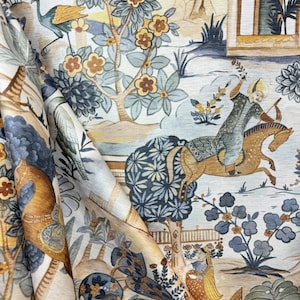 May include: A beige fabric with a blue and brown floral pattern. The fabric features a scene of a person riding a horse, a peacock, and a building with an archway.